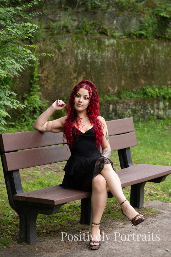 Jocelyn poses confidently near the Rocky River at David Fortier River Park in Olmsted Falls, Ohio by flowing water and lush greenery. Her senior portraits capture both elegance and adventure, with additional images highlighting stone textures, ivy-covered walls, and classic architecture. The session includes a bold look with a black dress and leopard heels, and ends with cap and gown photos by the riverside, celebrating her graduation.