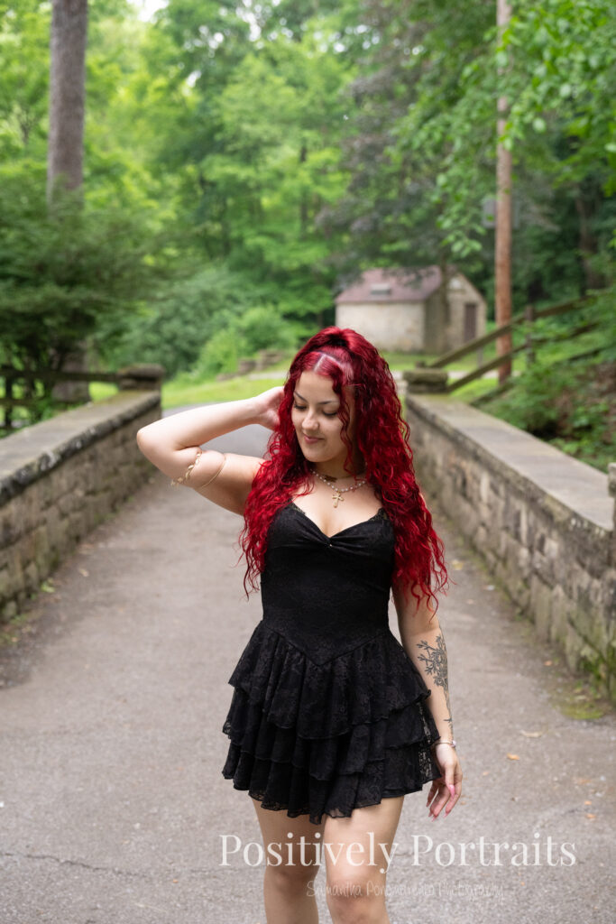 Jocelyn poses confidently near the Rocky River at David Fortier River Park in Olmsted Falls, Ohio by flowing water and lush greenery. Her senior portraits capture both elegance and adventure, with additional images highlighting stone textures, ivy-covered walls, and classic architecture. The session includes a bold look with a black dress and leopard heels, and ends with cap and gown photos by the riverside, celebrating her graduation.