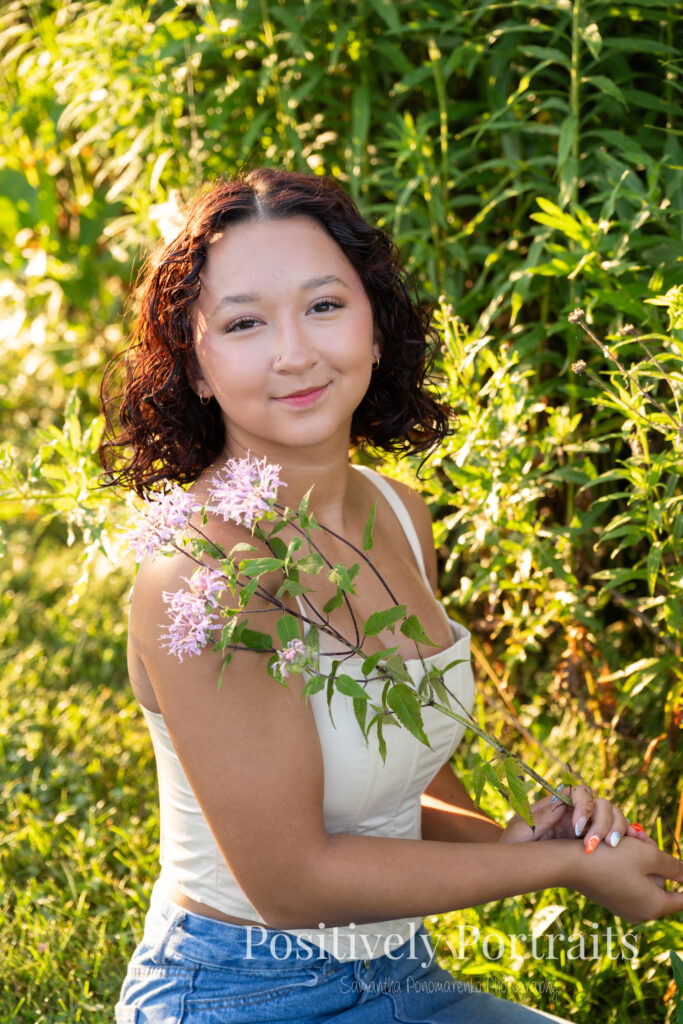 Emerson standing in a field of wildflowers at Brunswick Lake Park, early morning sunlight creating a dreamy glow around her.