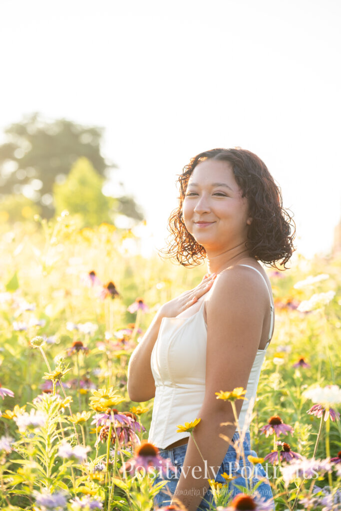 Emerson standing in a field of wildflowers at Brunswick Lake Park, early morning sunlight creating a dreamy glow around her.