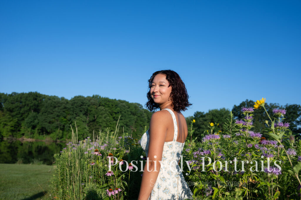 Emerson standing in a field of wildflowers at Brunswick Lake Park, early morning sunlight creating a dreamy glow around her.