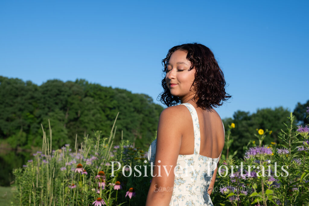 Emerson standing in a field of wildflowers at Brunswick Lake Park, early morning sunlight creating a dreamy glow around her.