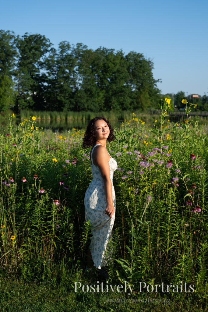 Emerson standing in a field of wildflowers at Brunswick Lake Park, early morning sunlight creating a dreamy glow around her.