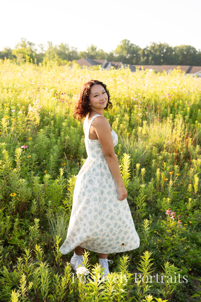 Emerson standing in a field of wildflowers at Brunswick Lake Park, early morning sunlight creating a dreamy glow around her.
