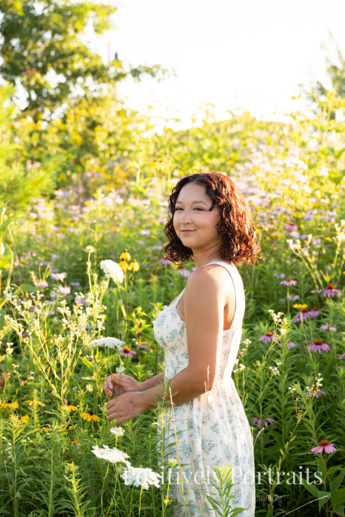 Emerson standing in a field of wildflowers at Brunswick Lake Park, early morning sunlight creating a dreamy glow around her.