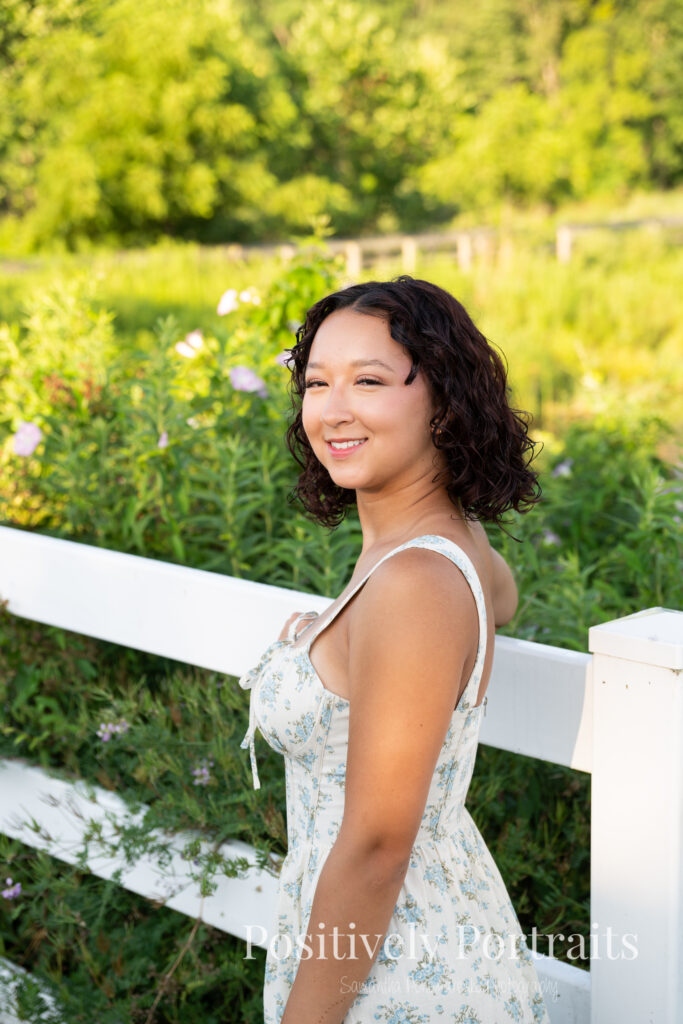 Emerson standing in a field of wildflowers at Brunswick Lake Park, early morning sunlight creating a dreamy glow around her.