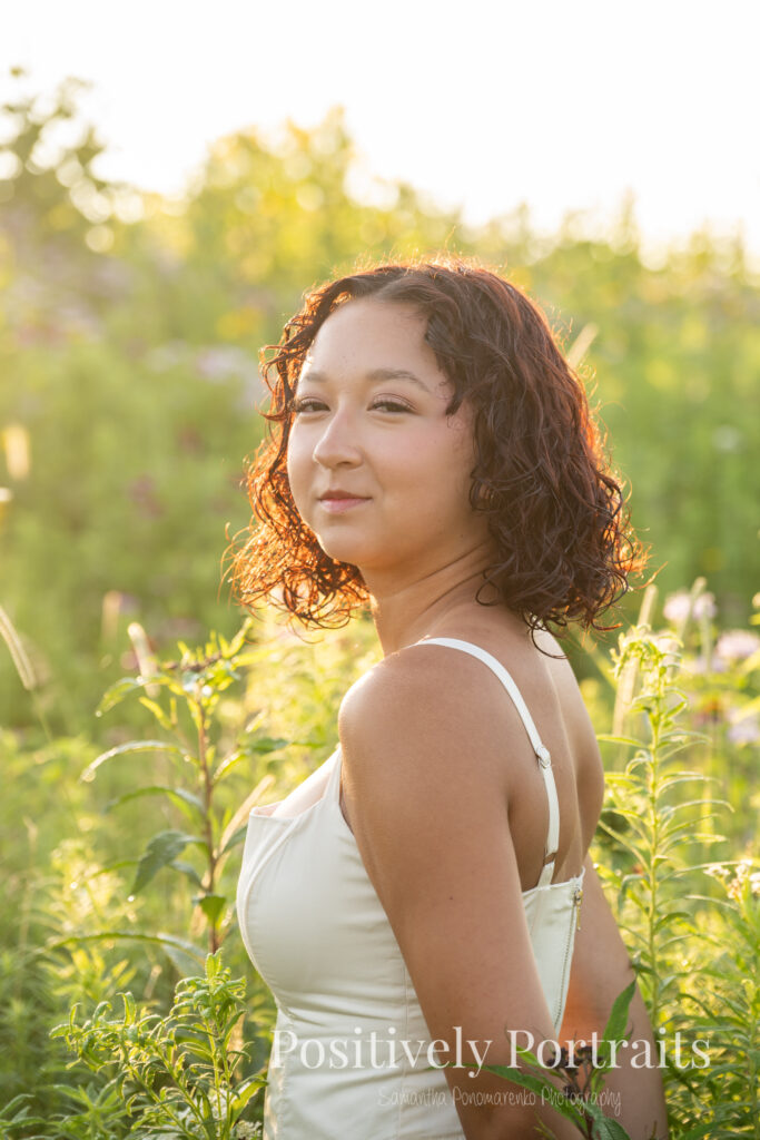 Emerson standing in a field of wildflowers at Brunswick Lake Park, early morning sunlight creating a dreamy glow around her.