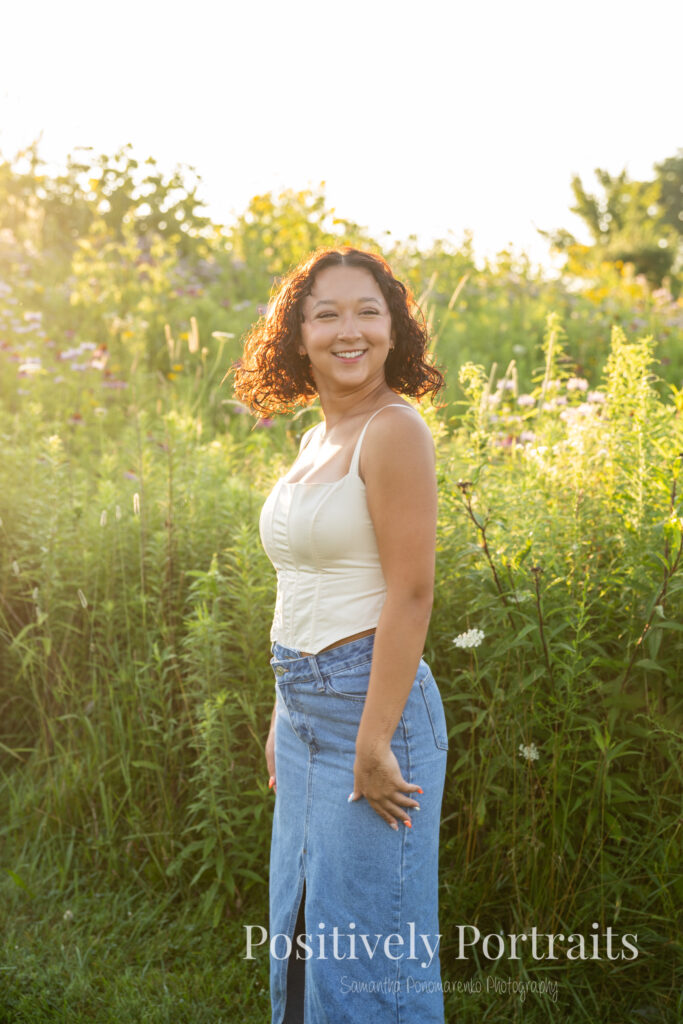 Emerson standing in a field of wildflowers at Brunswick Lake Park, early morning sunlight creating a dreamy glow around her.