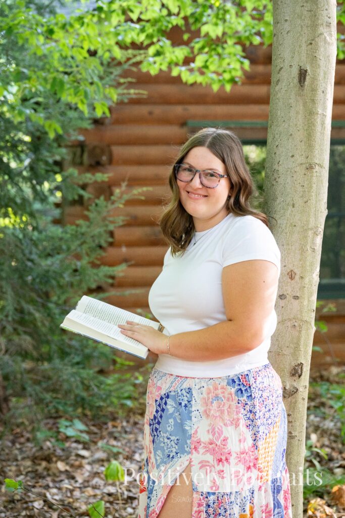 Tabitha in a white t-shirt and colorful patchwork skirt standing on a wooded trail at Brunswick Lake, her outfit’s vibrant patterns contrasting with the greenery.