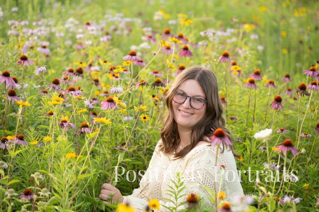 Tabitha standing by the lake’s edge at Brunswick Lake with soft ripples in the water, wearing a yellow sweater and jeans for her senior photos.