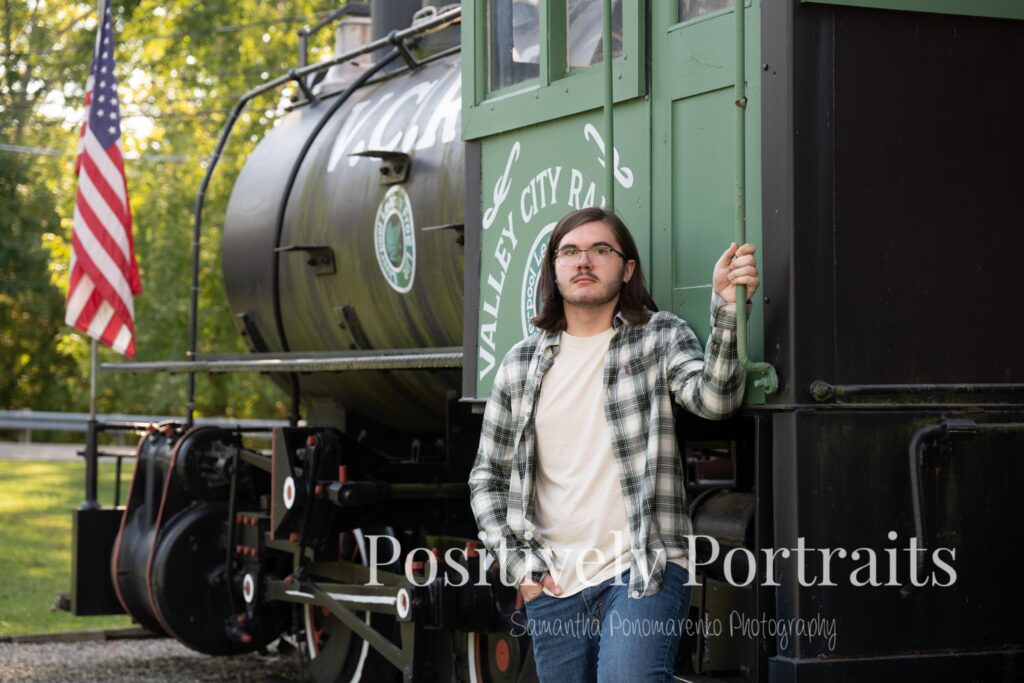 Senior photos of Jaxon in Valley City Ohio featuring the historic train depot, old tracks, log cabin, and stream at Mill Stream Park. The session highlights Jaxon’s vintage cameras and his creative personality, capturing a timeless and meaningful story.
